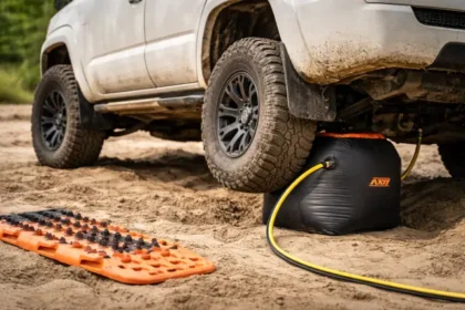 Airbag jack lifting an SUV on sand during off-road recovery with traction boards nearby
