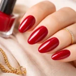red nail polish cherry manicure on neatly shaped nails with glossy finish, soft neutral background, and minimal luxury accessories, no text